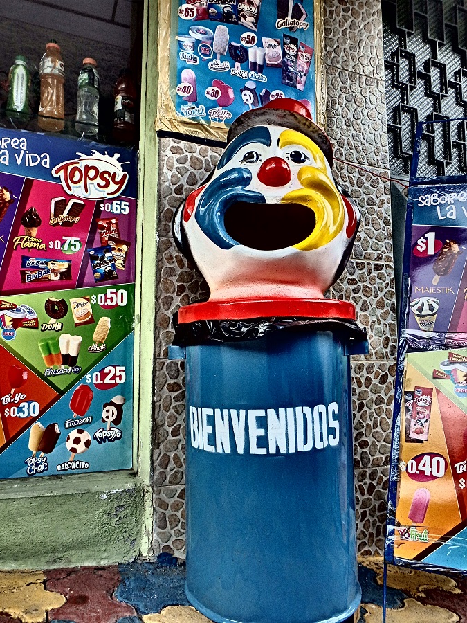 A bin with a giant clown's head stating 'welcome' in Spanish
